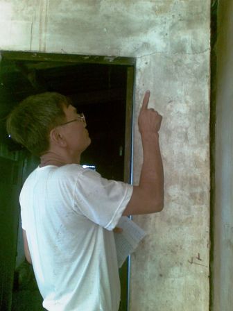 Ông Phú đang kiểm tra các vết nứt trên tường nhà.