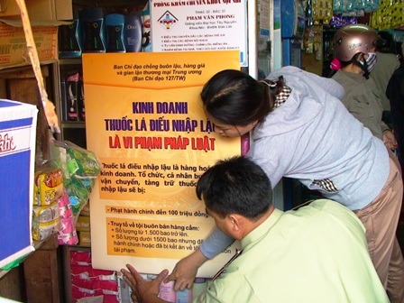 Cán bộ đội 1 - Chi cục QLTT dán áp phích tuyên truyền và tổ chức ký cam kết không kinh doanh thuốc lá điếu nhập lậu tại địa bàn TP. Buôn Ma Thuột.