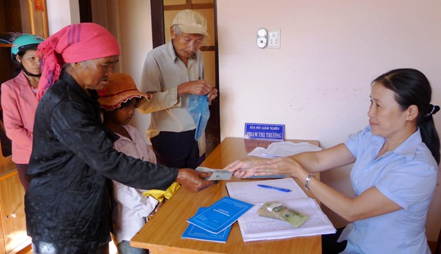 Chị Phạm Thị Hương đang chi trả chế độ cho những người được hưởng chế độ bảo trợ xã hội.