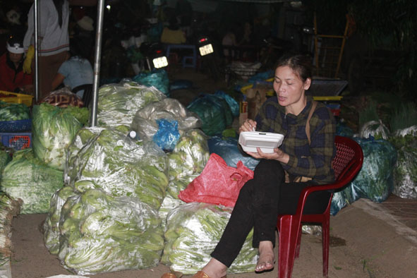 Một người làm bốc vác tranh thủ ăn trước khi chuyến xe hàng khác đến.