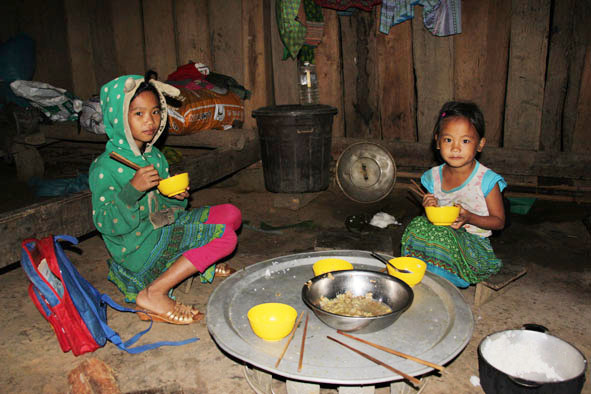 Em Sùng Thị Say đang ăn cơm để chuẩn đến trường.