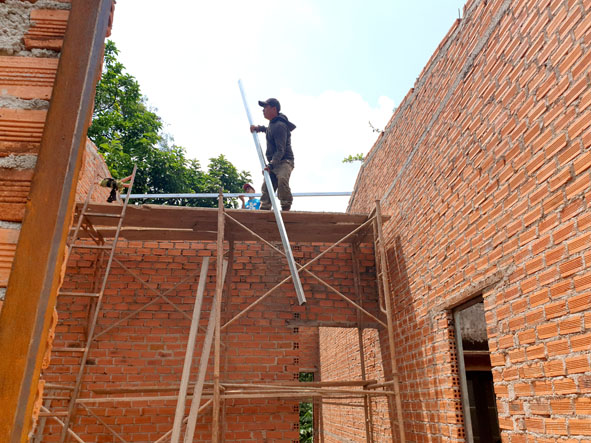 Thành viên đội thợ xây đang lắp kèo sắt cho nhà chị H’ Sơly.