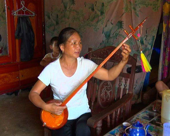 Bà Mậu chơi đàn tính và hát then.