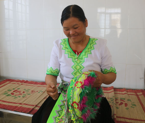 Chị Đào Thị Xía (thôn Ea Khiêm) đang chỉnh sửa lại mũ đội đầu của mình.