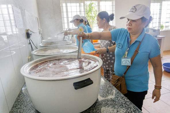Bà Phạm Thị Mai (bìa phải) nấu cháo từ thiện tại Bệnh viện Đa khoa vùng Tây Nguyên.  