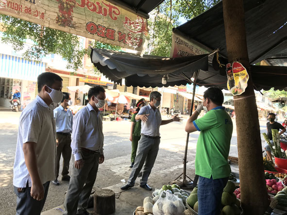 Cơ quan chức năng tuyên truyền, nhắc nhở tiểu thương ở chợ Thị trấn Quảng Phú thực hiện công tác phòng chống dịch.